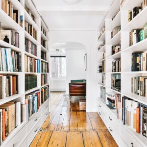 Vue intérieure d'une bibliothèque élégante sur son parquet d'époque massif dans une maison rénovée à neuf, reflétant un design typique et des étagères bien agencées avec une large sélection de livres, soulignant le confort et le style de vie raffiné proposé par Villas Terre & Pierre