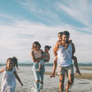 Photographie d'une famille heureuse, les pieds dans l'eau, symbolisant la réussite de leur projet de villa sur mesure au Pays Basque, grâce à des choix judicieux évitant les erreurs courantes.